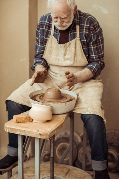 Vista frontale dell'artigiano maschile che lavora sulla ruota dei vasai
 - Foto, immagini