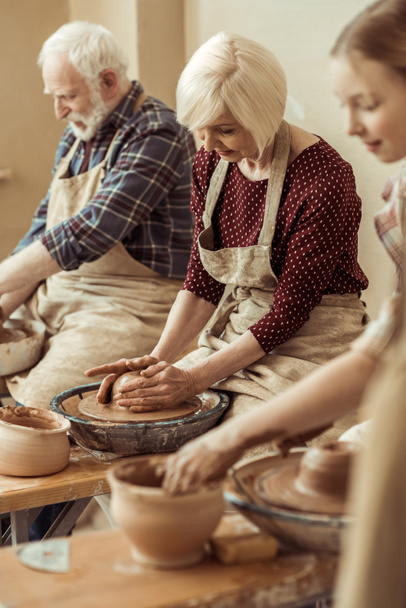 Grand-mère et grand-père avec petite-fille faire de la poterie à l'atelier
 - Photo, image