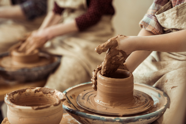 Primer plano de las manos de los niños que trabajan en la rueda de cerámica en el taller
 - Foto, imagen