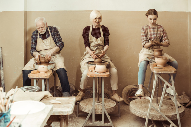 Grandmother and grandfather with granddaughter making pottery at workshop - Photo, Image