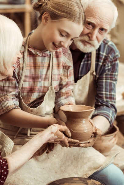 Grandmother and grandfather with granddaughter making pottery at workshop - Foto, Imagen