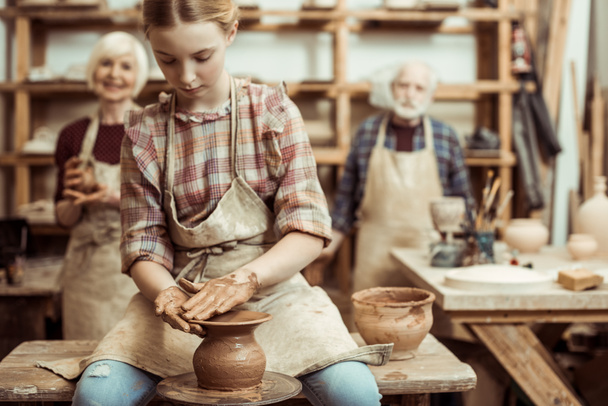 Abuela y abuelo con nieta haciendo cerámica en el taller
 - Foto, Imagen