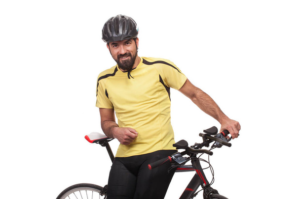 Porträt eines lächelnden Radfahrers mit Helm und gelbem Hemd, der mit einem Fahrrad posiert, isoliert auf weißem Hintergrund - Foto, Bild