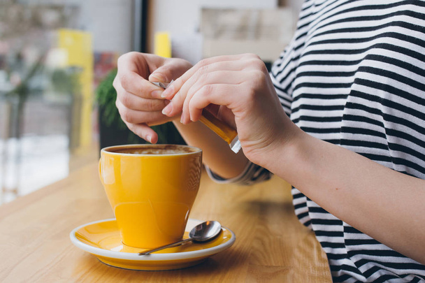 Girl pours sugar from a bag into a mug of coffee - Zdjęcie, obraz