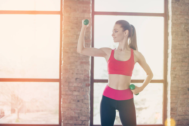 Young sportgirl is working out with dumbbells in bright warm roo - Fotoğraf, Görsel
