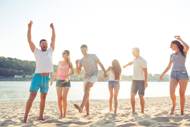 Groupe de personnes gaies faisant la fête à la plage et dansant
 - Photo, image
