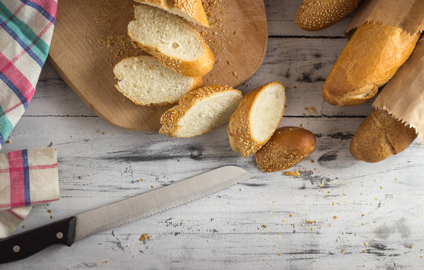 French baguette cut with a knife on cutting board - Photo, image