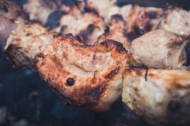 Het grillen van vlees van de barbecue op houtskool. Man kookt smakelijk warm shish kebab op metalen spiesen. De stukken van het smakelijke vlees met korst. Grillen voedsel. Koken sjasliek op barbecue grill. Closeup - Foto, afbeelding