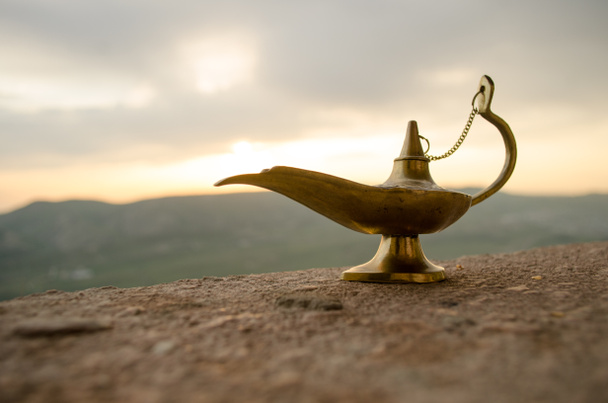 Antiguo artesanal Aladdin Arabian noches genio estilo lámpara de aceite con humo blanco luz suave. Fondo de montaña atardecer
 - Foto, Imagen