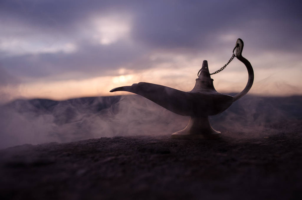 Antiquité artisanale Aladdin Arabian nuits lampe à huile de style génie avec douce lumière fumée blanche. Coucher de soleil fond de montagne
 - Photo, image