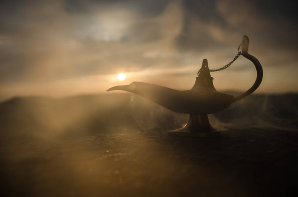 Антикварная ремесленная арабская ночь Аладдина в стиле джинна масляная лампа с мягким белым дымом. Закат горы
 - Фото, изображение