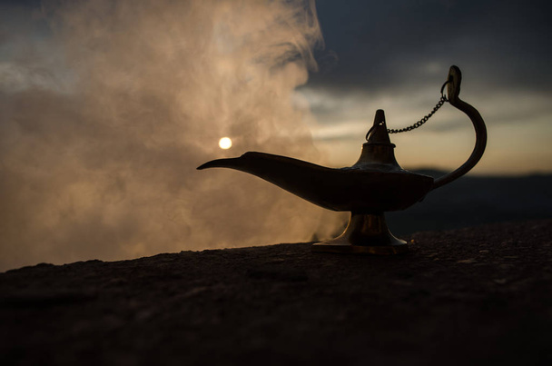 アンティーク職人アラジン アラビアン魔神スタイル石油ランプと柔らかい光の白い煙があります。夕日山を背景 - 写真・画像