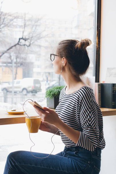 Girl listening to music on your smartphone and drinking coffee - Valokuva, kuva
