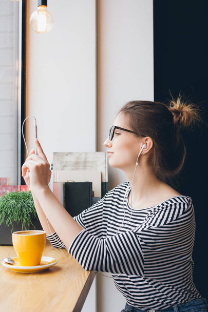 Girl makes selfie on smartphone in coffee shop - Fotoğraf, Görsel