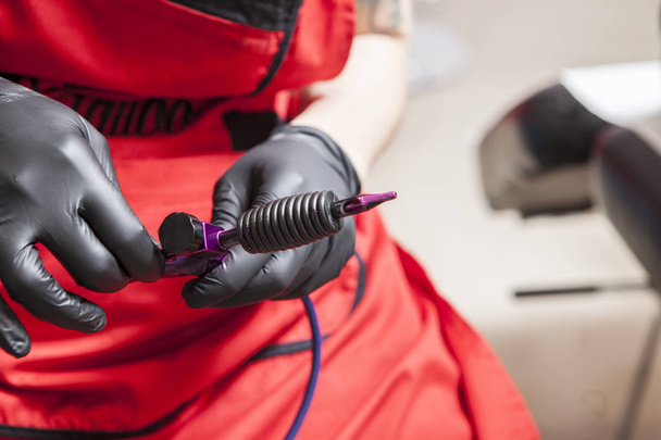 Καλλιτέχνης τατουάζ ρυθμίζεται μελάνι μηχανής όπλο - Φωτογραφία, εικόνα