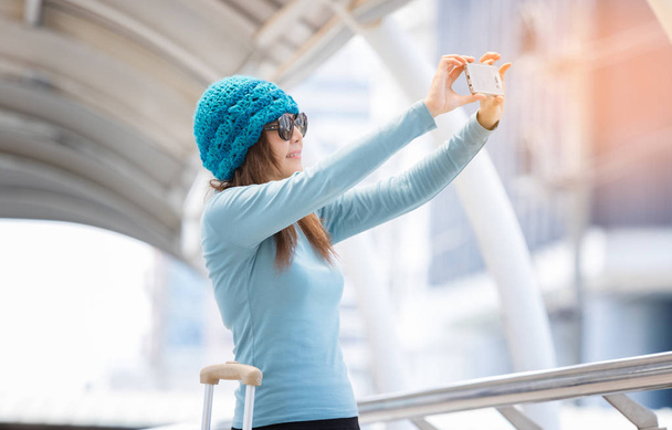 Mujer joven tomando selfie con bolsas de viaje durante el viaje
 - Foto, Imagen