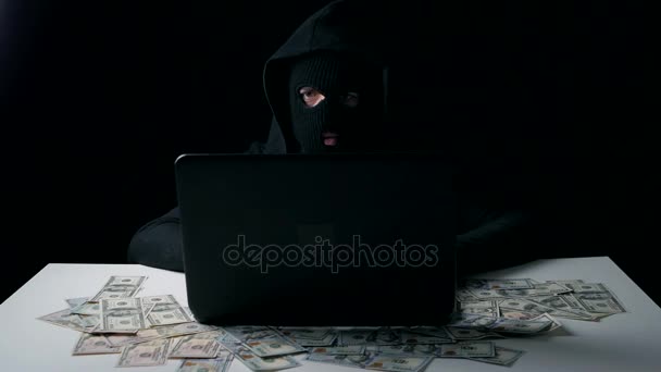 A hacker in a balaclava earns money. Cyber crime. - Footage, Video