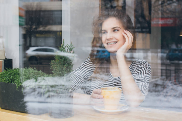 Girl drinking coffee in a coffee shop - Фото, изображение