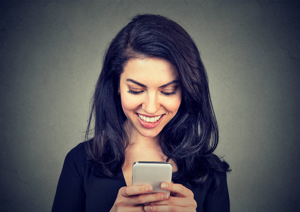 Laughing woman text messaging on smart phone having a pleasant chart conversation  - Valokuva, kuva