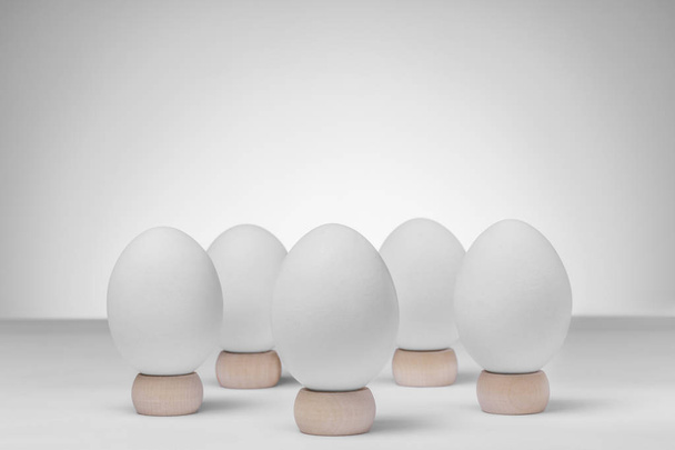 Пять белых куриных яиц на деревянных стендах на белом фоне для копирования пространства
 - Фото, изображение