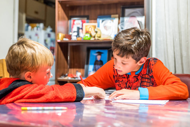 Dos chicos escribiendo una carta a Santa Claus en la mesa
 - Foto, Imagen