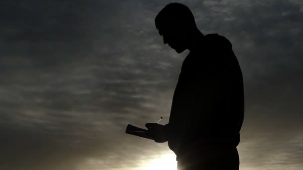 Zwarte silhouet van een Man die Down in zijn notitieblok schrijft. - Video