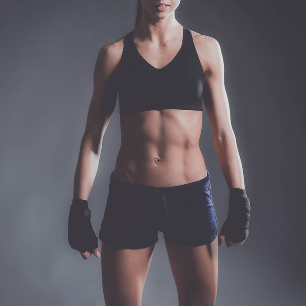 Musclé jeune femme posant en vêtements de sport sur fond noir
 - Photo, image