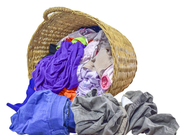 Много одежды в плетеной корзине на изолированном белом фоне
 - Фото, изображение