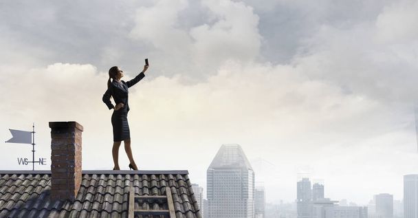 Nainen katolla tekemässä selfietä. Sekalaiset tiedotusvälineet
 - Valokuva, kuva