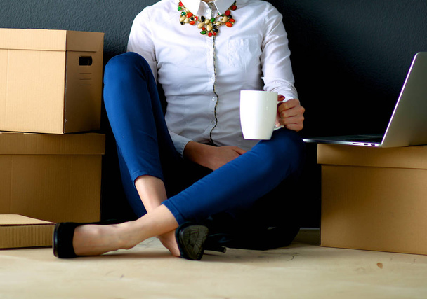 femme assise sur le sol près d'une boîte avec ordinateur portable - Photo, image