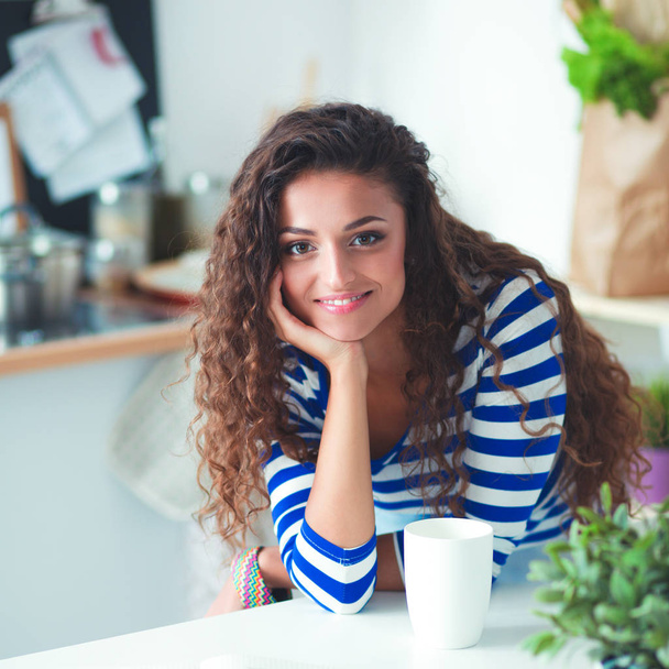 Smiling young woman with laptop in the kitchen at home - Foto, Imagen