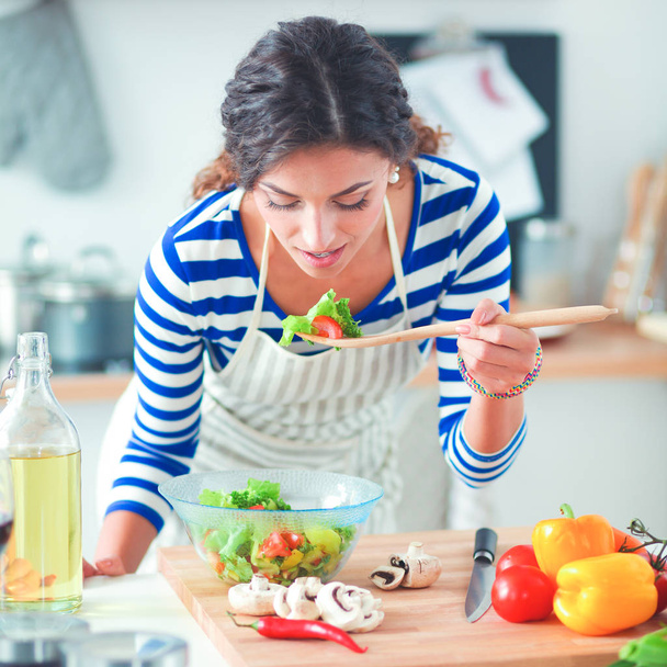 Young woman eating fresh salad in modern kitchen - Foto, Imagem
