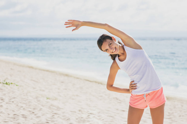 sporty woman smiling while doing body stretching - Fotoğraf, Görsel