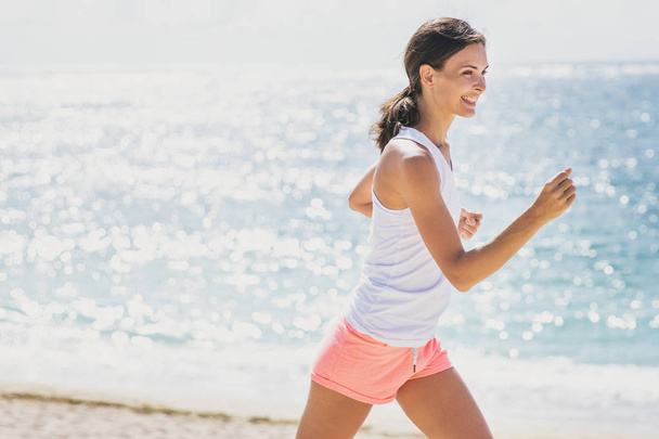 sporty woman jogging with skies and sea at the background - Photo, Image