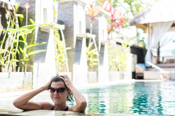 Mujer joven en traje de baño en piscina en magnífico complejo, villa de lujo, isla tropical de Bali, Indonesia
. - Foto, imagen