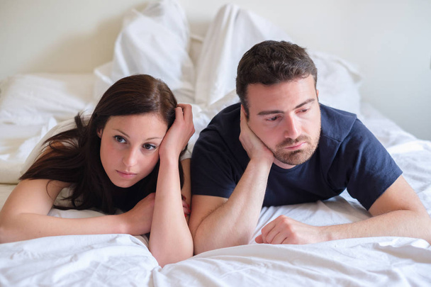 Ανησυχούν και βαριούνται εραστές ζευγάρι μετά από μια πάλη ξαπλωμένη στο κρεβάτι - Φωτογραφία, εικόνα