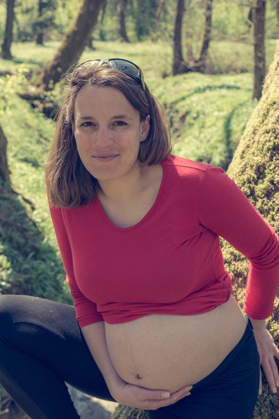 Fiatal terhes nő pózol park. - Fotó, kép