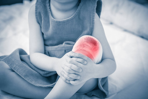Kind verletzt. Wunde am Knie des Kindes mit Verband. Humanes Gesundheits- und Medizinkonzept.  - Foto, Bild