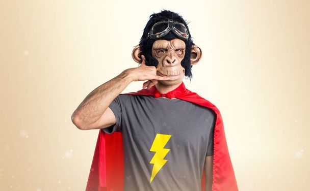 Superhelden-Affenmann macht Handygeste auf ockerfarbenem Hintergrund - Foto, Bild