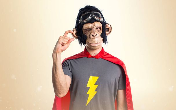 Superheld monkey man doen kleine aanmelden okergeel achtergrond - Foto, afbeelding