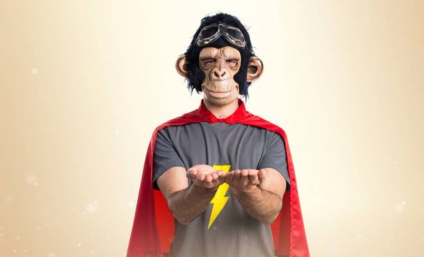Supereroe scimmia uomo in possesso di qualcosa su sfondo ocra
 - Foto, immagini