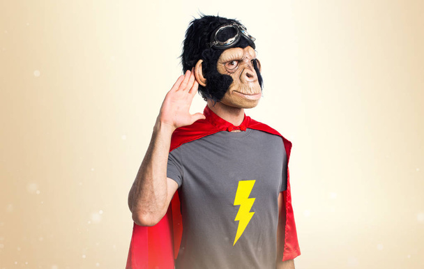 Superhero monkey man listening something on ocher background - Photo, Image