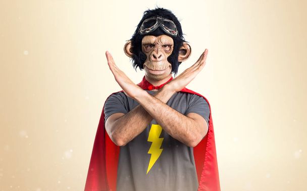 Superhéroe mono hombre haciendo NO gesto sobre fondo ocre
 - Foto, imagen