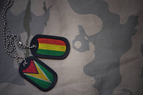 army blank, dog tag with flag of bolivia and guyana on the khaki texture background. military concept - Photo, Image