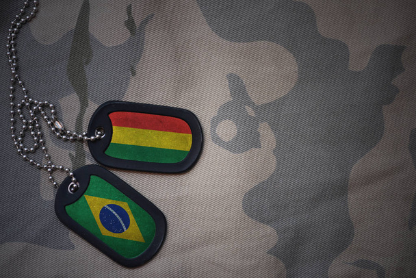 army blank, dog tag with flag of bolivia and brazil on the khaki texture background. military concept - Photo, Image