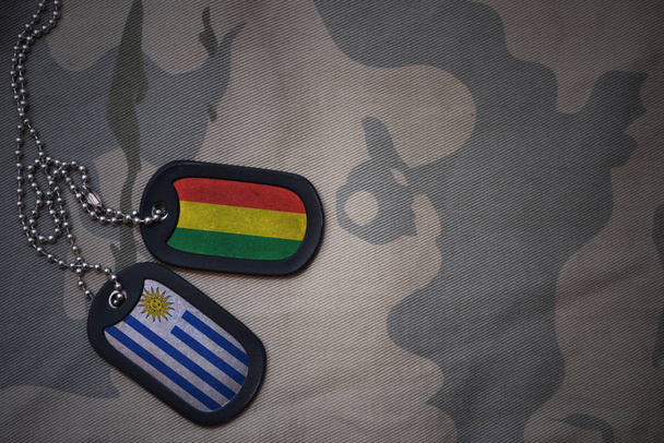 army blank, dog tag with flag of bolivia and uruguay on the khaki texture background. military concept - Photo, Image