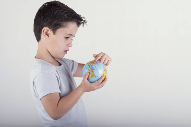 Boy looking at a toy globe. child holding earth in hands - Photo, Image