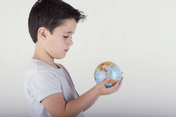 Хлопчик дивиться на іграшковий глобус. дитина тримає землю в руках
 - Фото, зображення