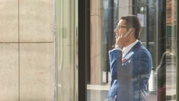Office worker talking on phone outside hotel - Materiaali, video