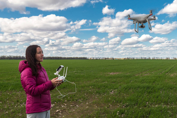 chica operando de avión no tripulado volador quadrocopter en el campo verde
 - Foto, Imagen